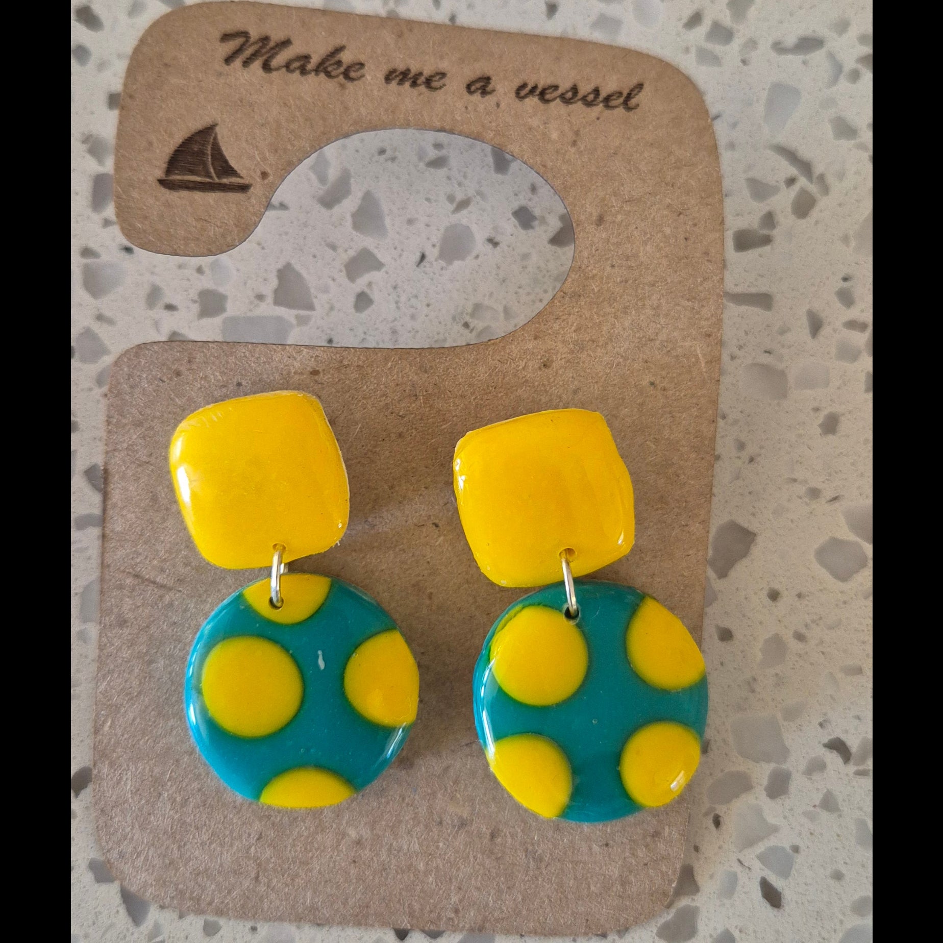 Pair of yellow and blue polka dot earrings on a cardboard backing with 'Make me a wish' text.