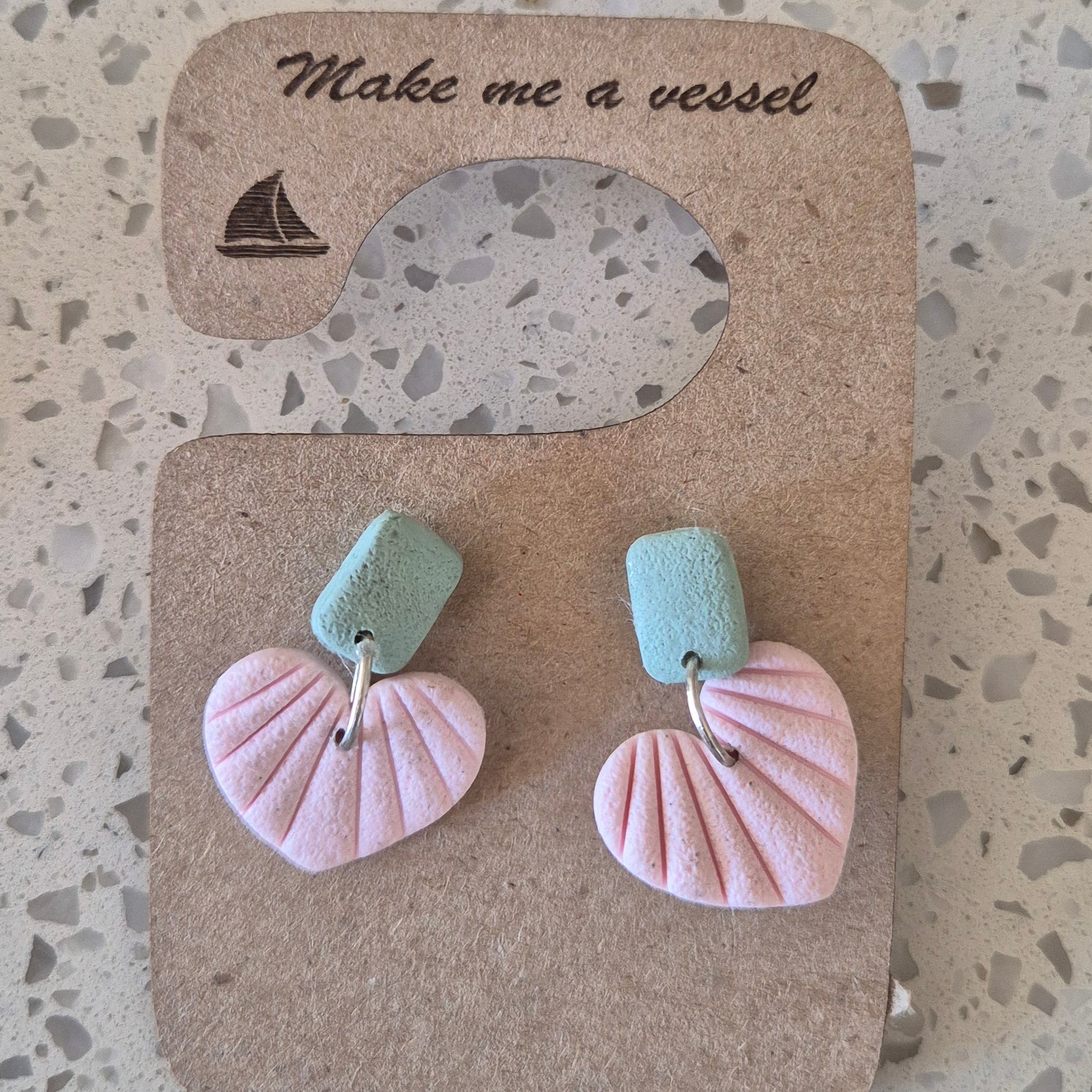 Pair of pink and green earrings on a cardboard backing with 'Make me a card' text.